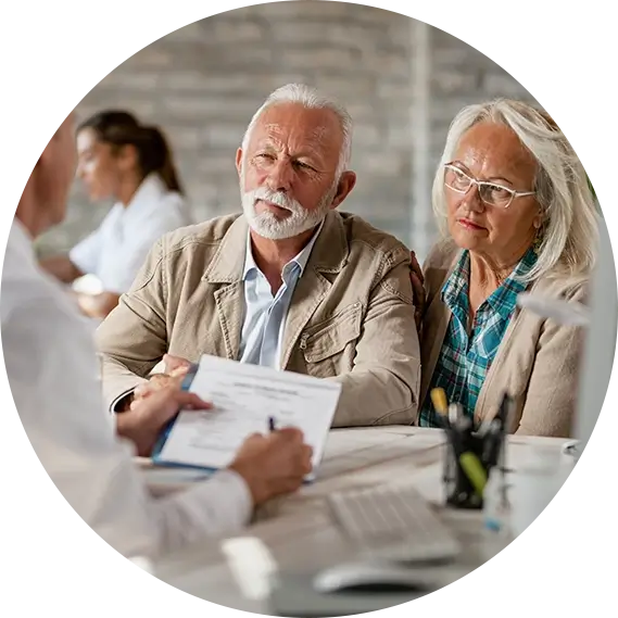 An elderly man and woman in an office setting discussing insurance needs with agent