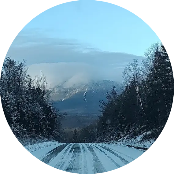 perspective view of snow covered road leading to mountain in the distance